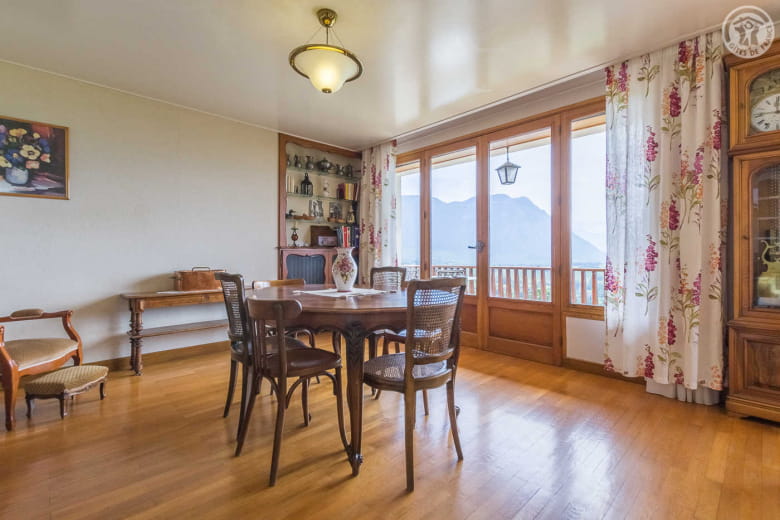 Salle à manger avec grande baie vitrée ouvrant sur le balcon